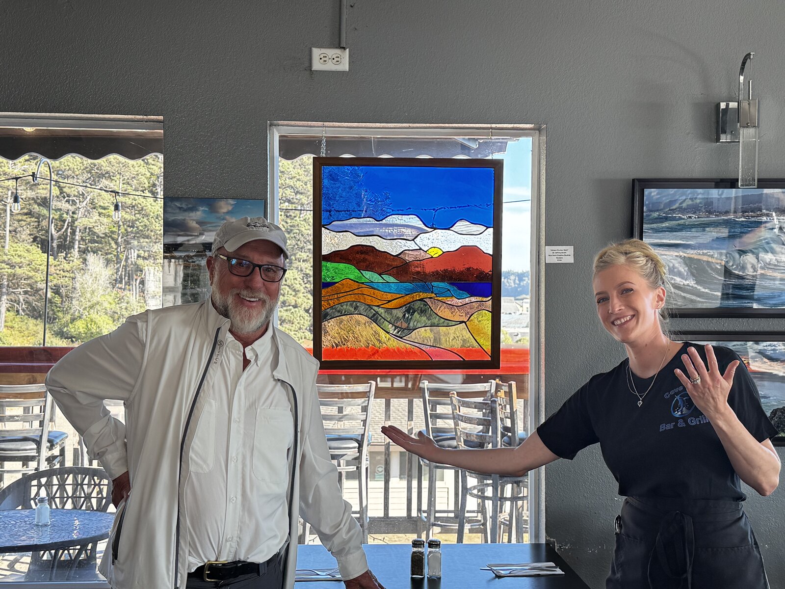 Where the Sun Rests hanging in the window at Cove Azul Bar & Grill, with Dr. Duckham and the owner