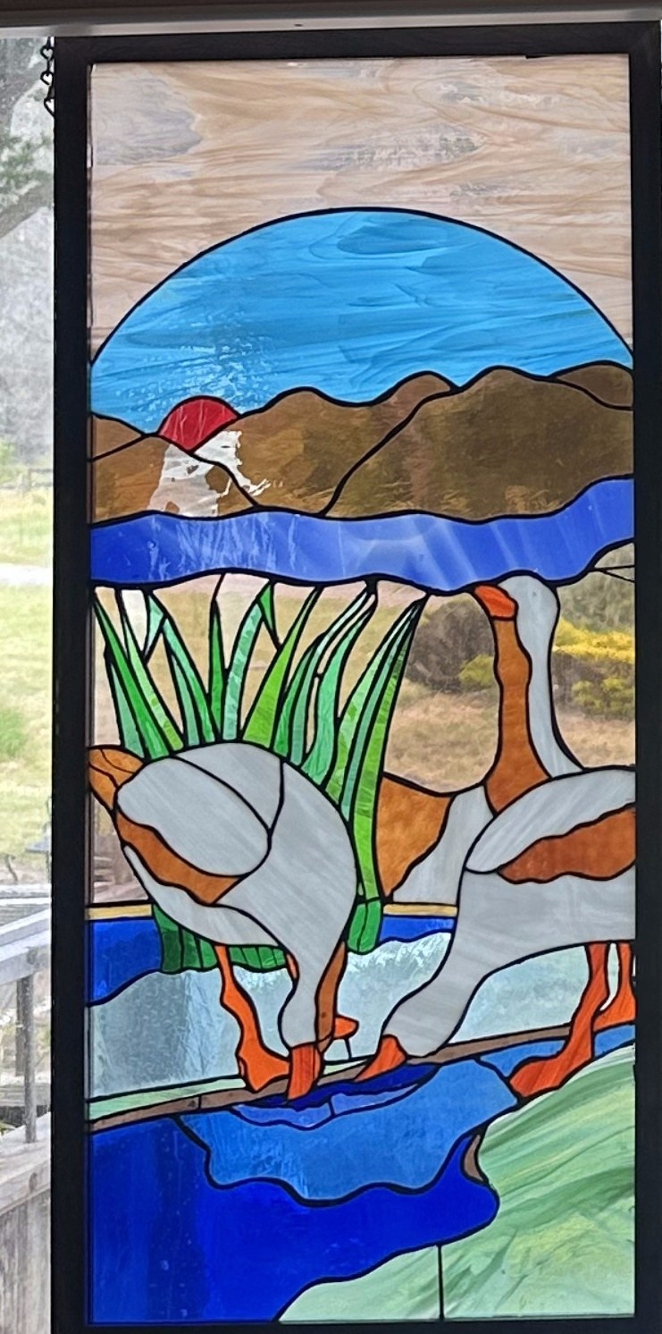 Stained glass window of geese in a marsh, left panel